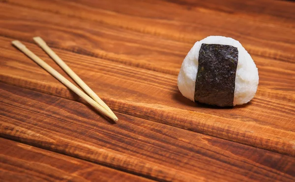Japanisches onigiri mit Essstäbchen auf Holzgrund. Reiskugel — Stockfoto