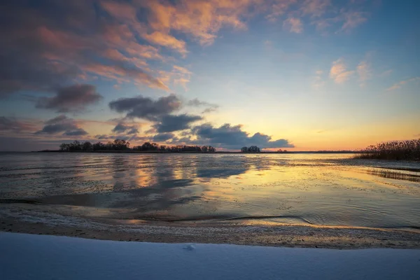 Zimní krajina se zamrzlým jezerem a zapadajícím nebem. — Stock fotografie