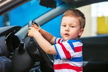 Sevimli küçük çocuk arabada oturan ve tekerleği tutar