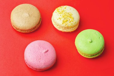 Tasty farklı macaroons kırmızı arka plan üzerinde renkli