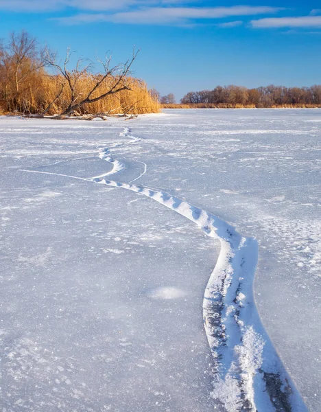 Paisaje invernal con grietas, enganche, cañas y río congelado — Foto de Stock