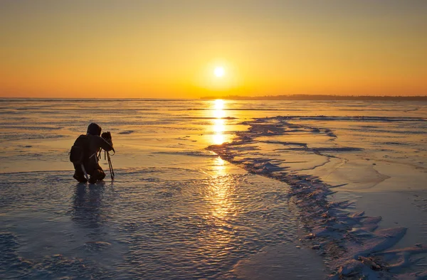 Fotograf tar bilder på isen under solnedgången — Stockfoto