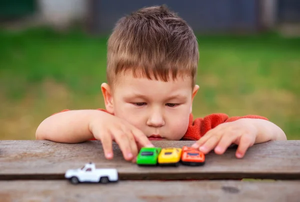 小さな男の子は、カラフルなおもちゃの車で遊ぶ。自動車と遊ぶ子供 — ストック写真