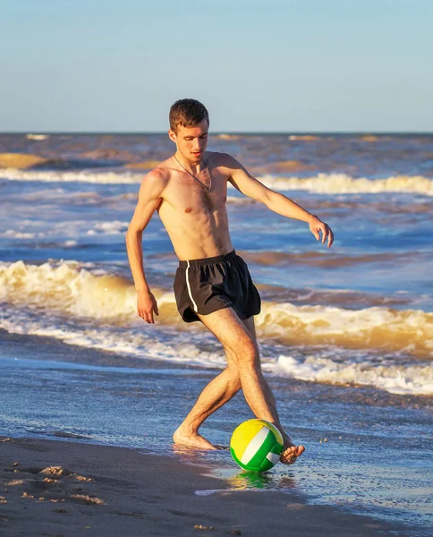 Homens jogando futebol na costa da praia ao pôr do sol — Fotografia de Stock
