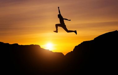 Silhouette of athlete, jumping over rocks in mountain area again clipart