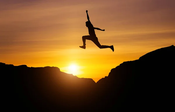 Silhouet van atleet, springen over rotsen in de bergen weer — Stockfoto