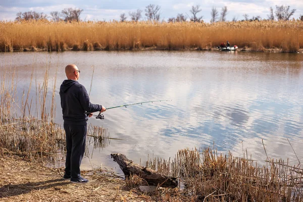 Un pescador con caña de pescar en la orilla del río . — Foto de Stock