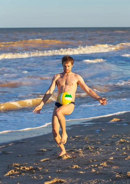 Homens jogando futebol na costa da praia ao pôr do sol — Fotografia de Stock
