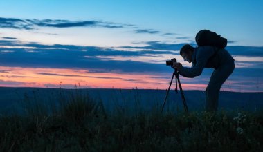 Bir fotoğrafta bir tripod kullanarak profesyonel bir fotoğrafçı silüeti 
