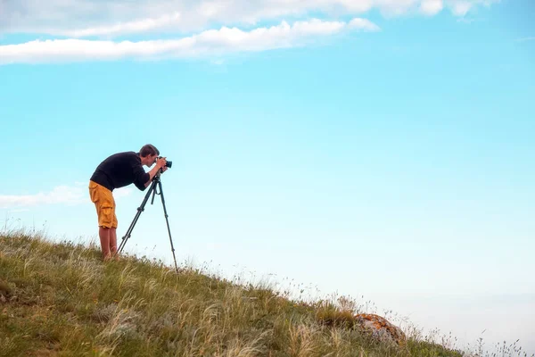 Ein Fotograf mit Stativ und Kamera macht Fotos von Landschaften am Berg — Stockfoto