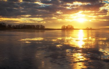Kış manzara nehir, sazlık ve bulutlu gökyüzü günbatımı. Yarışmaların