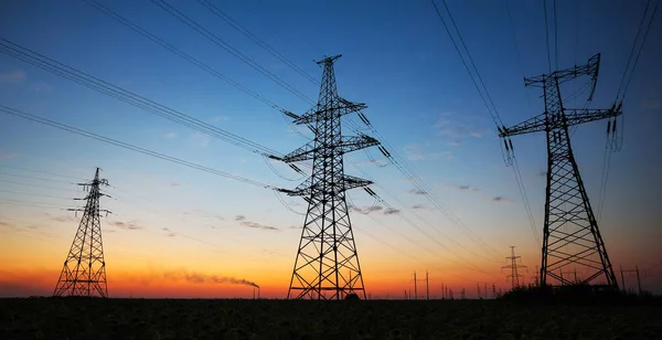 전기 pylons 일몰에 분야에 높은 전압 파워 라인의 실루엣 — 스톡 사진