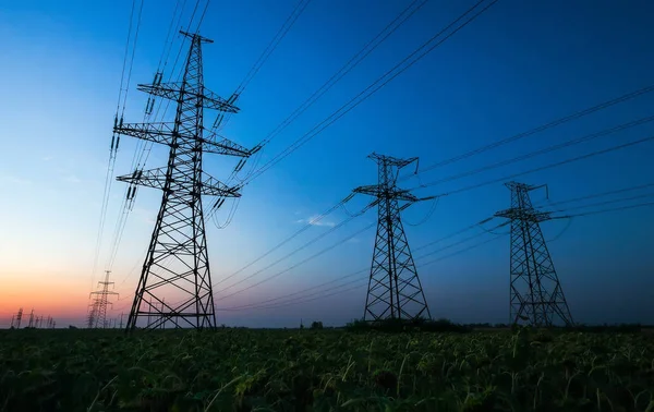 Sylwetki słupów energii elektrycznej i linii wysokiego napięcia na — Zdjęcie stockowe