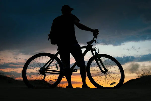 Silhuetten av cyklist på bakgrunden av solnedgången. Biker med bi — Stockfoto