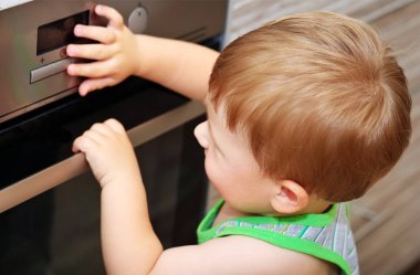 Mutfakta tehlikeli bir durum. Elektrikli fırın ile oynayan çocuk
