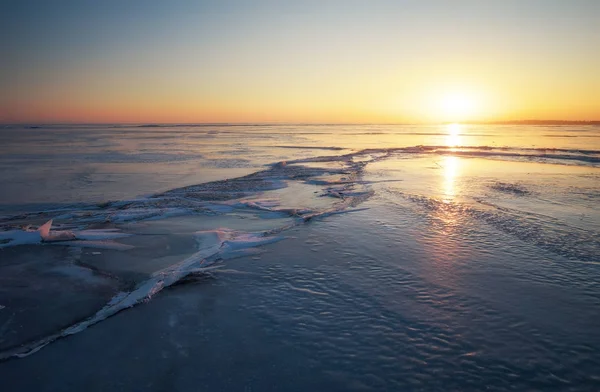 Зимний пейзаж с трещинами на замёрзшем озере у берега — стоковое фото