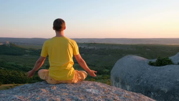 Здоровые молодые люди практикуют йогу на высокой горе на закате — стоковое видео