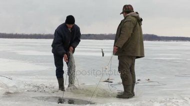 Fishermens donmuş bir havuzda delikten balık çekin. Balık tutma kış