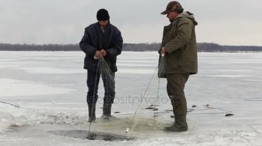 Fishermens donmuş bir havuzda delikten balık çekin. Balık tutma kış
