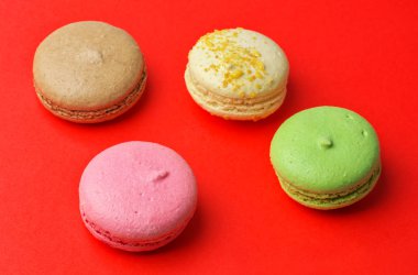Tasty farklı macaroons kırmızı arka plan üzerinde renkli