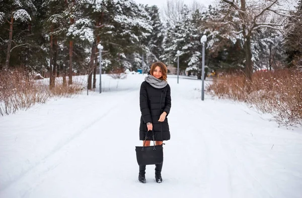 Beautiful young girl with bag in hand in park in winter time — Stock Photo, Image