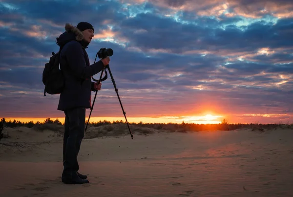 Fotograf strzela krajobrazy podczas zachodu słońca na piasku — Zdjęcie stockowe