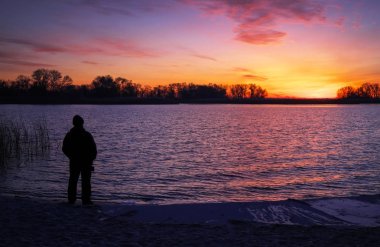 Yaşlı adam gündoğumu sahilde hayran. 