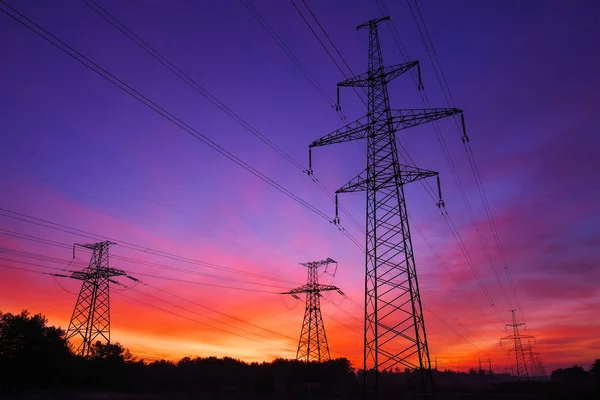 High-voltage power lines during fiery sunrise — Stock Photo, Image