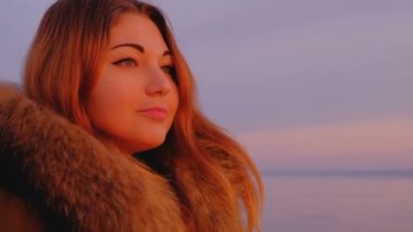 Gün batımında denize yakın poz uzun saçlı ihale kız. Güzel bir kadın sabah parlak renkli gündoğumu hayran