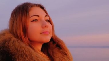 Gün batımında denize yakın poz uzun saçlı ihale kız. Güzel bir kadın sabah parlak renkli gündoğumu hayran