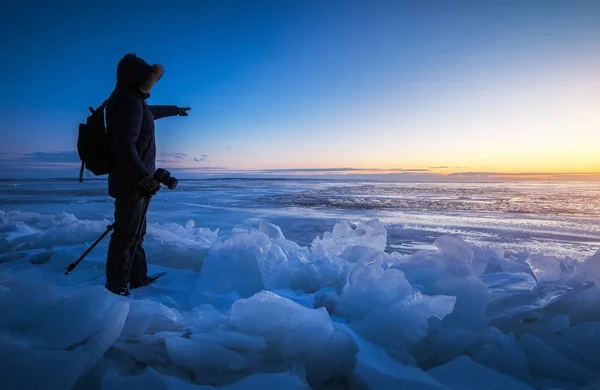 Фотограф фотографирует замерзшую реку на закате . — стоковое фото
