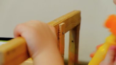 Küçük oyuncak çekiçle oynayan çocuk. Çocuk bir ahşap raylı bir çivi çivi. Onarım sandalye