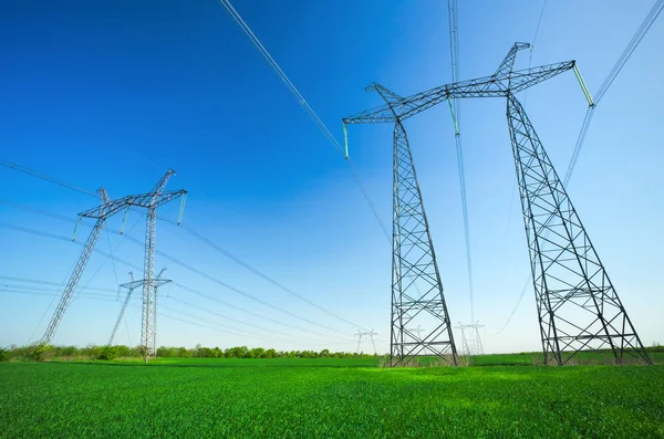 High voltage lines and power pylons in a green agricultural landscape — Stock Photo, Image