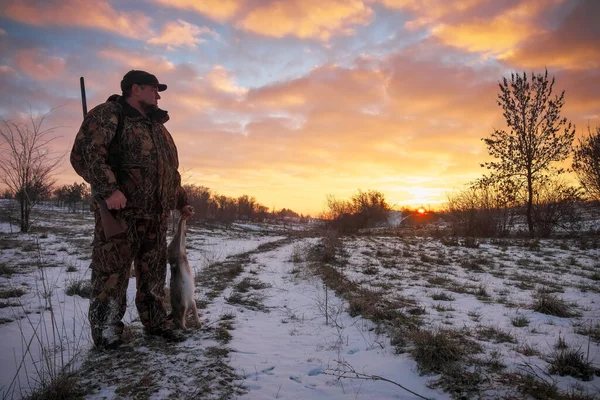 Zimowe polowanie na zające o wschodzie słońca. Hunter rusza się ze strzelbą. — Zdjęcie stockowe