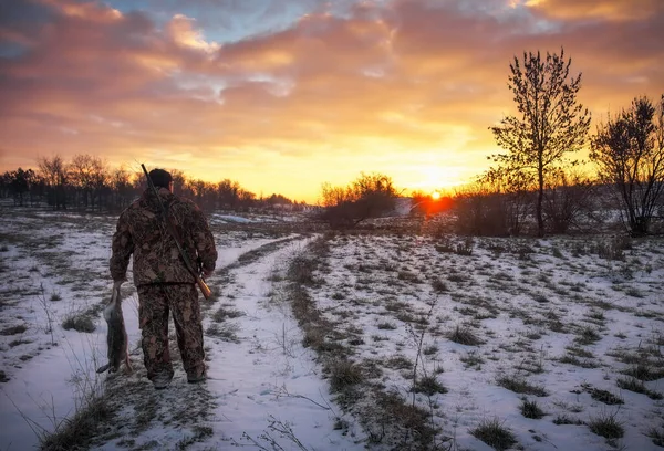 Zimowe polowanie na zające o wschodzie słońca. Hunter rusza się ze strzelbą. — Zdjęcie stockowe