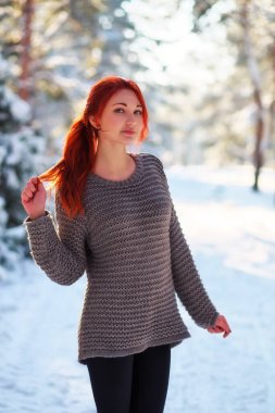 Beautiful charming girl with red hair in the winter park. Pensiv