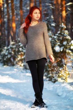 Beautiful charming girl with red hair in the winter park. Pensiv