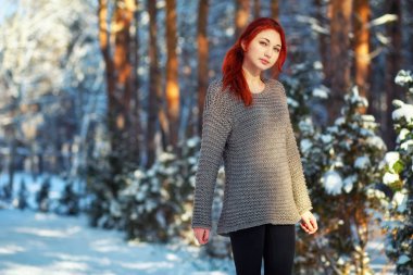 Beautiful charming girl with red hair in the winter park. Pensiv