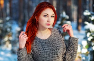 Beautiful charming girl with red hair in the winter park. Pensiv