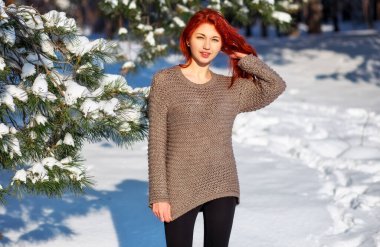 Beautiful charming girl with red hair in the winter park. Pensiv