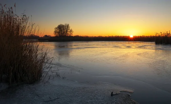Zimní krajina s západu slunce na obloze a zamrzlou řeku. Za úsvitu — Stock fotografie