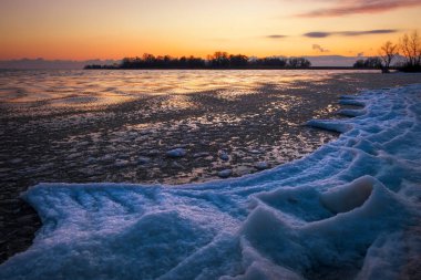Gün doğumu ve donmuş nehir. Sabah vakti gölü olan güzel bir kış manzarası. Şafak vakti