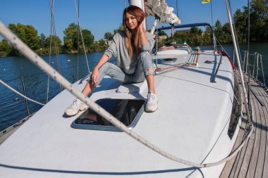 Yatta poz veren güzel bir genç kadın. Modeller gemiye biniyor.