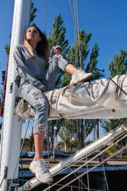 Yatta poz veren güzel bir genç kadın. Modeller gemiye biniyor.