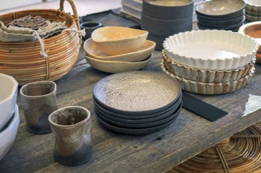 Antika yemekler ve ahşap bir masanın üzerindeki diğer orijinal şeyler. Tabaklar, sepetler, vazolar, kitaplar