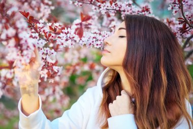 Gün batımında şeftali ağacının yanında duran gülümseyen güzel kız. Gülen surat. Bahar geldi..