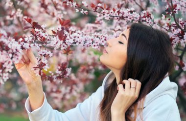 Gün batımında şeftali ağacının yanında duran gülümseyen güzel kız. Gülen surat. Bahar geldi..