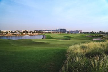 Stunning panoramic view of the green golf course on a background of beautiful blue sky.