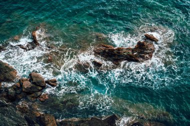 Derin mavi Akdeniz dalgalarının kayalık kayalıklara çarpmasının havadan görüntüsü.
