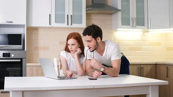 Happy couple looking at laptop at home in the kitchen, what was discussed